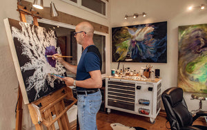 Christopher M. Sullivan works on a new painting in his studio gallery in Angel Fire, New Mexico, surrounded by his painting supplies and other finished pieces.